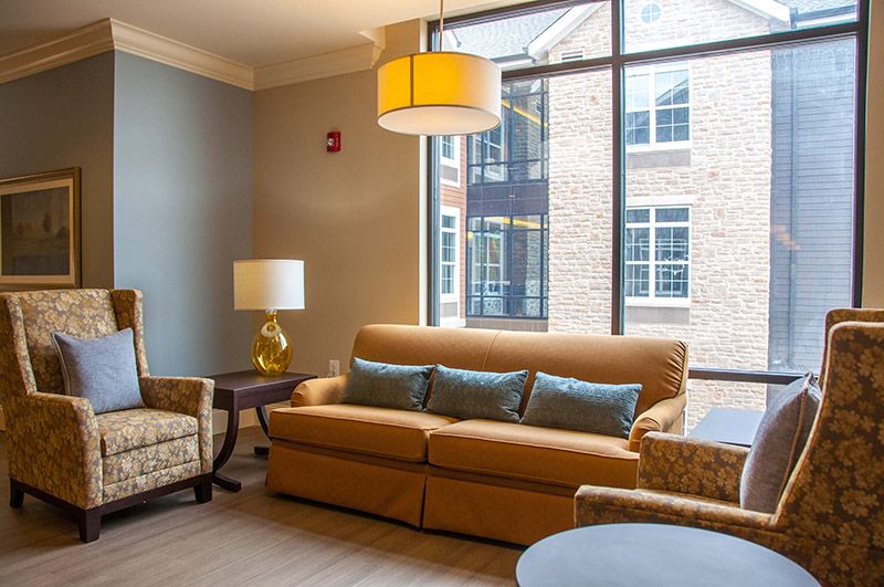 A cozy living room with a sofa, chairs, and large window.