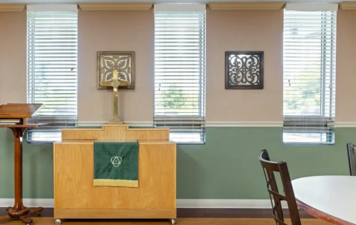 A simple chapel interior featuring an altar with a cross and religious decor on the walls.