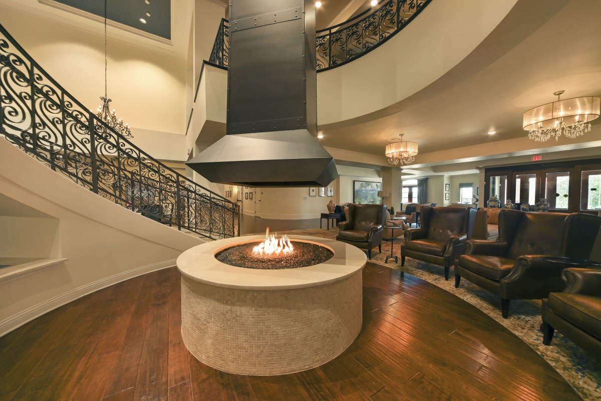 A luxurious living room featuring a modern fireplace, spiral staircase, and elegant seating.