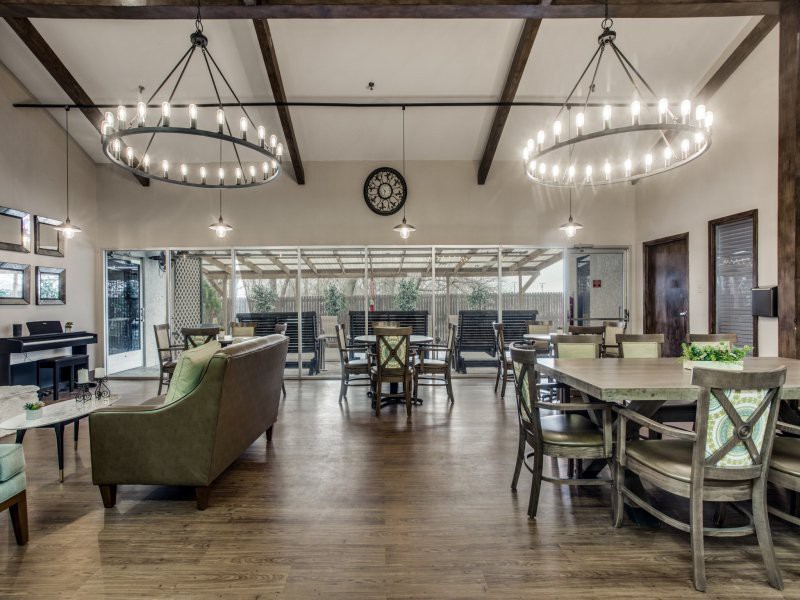A spacious dining area with chandeliers, wooden flooring, and comfortable seating.