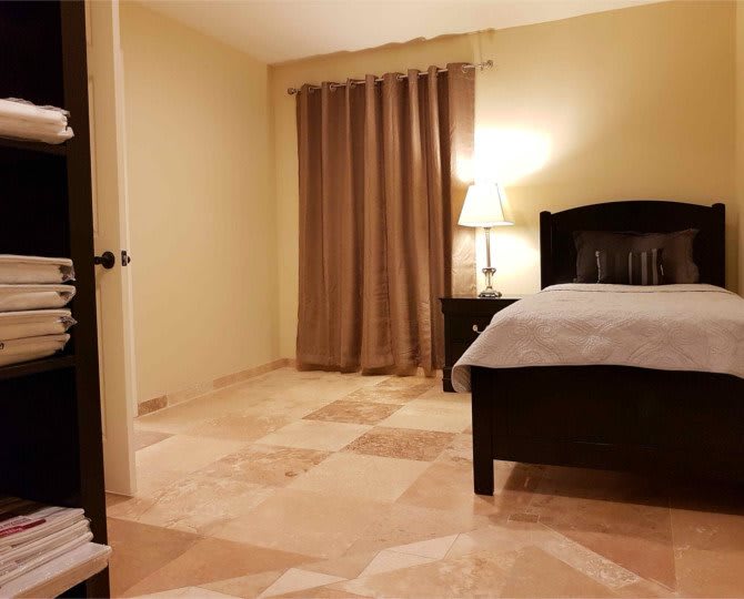 A warmly lit bedroom featuring a bed, lamp, and curtains.