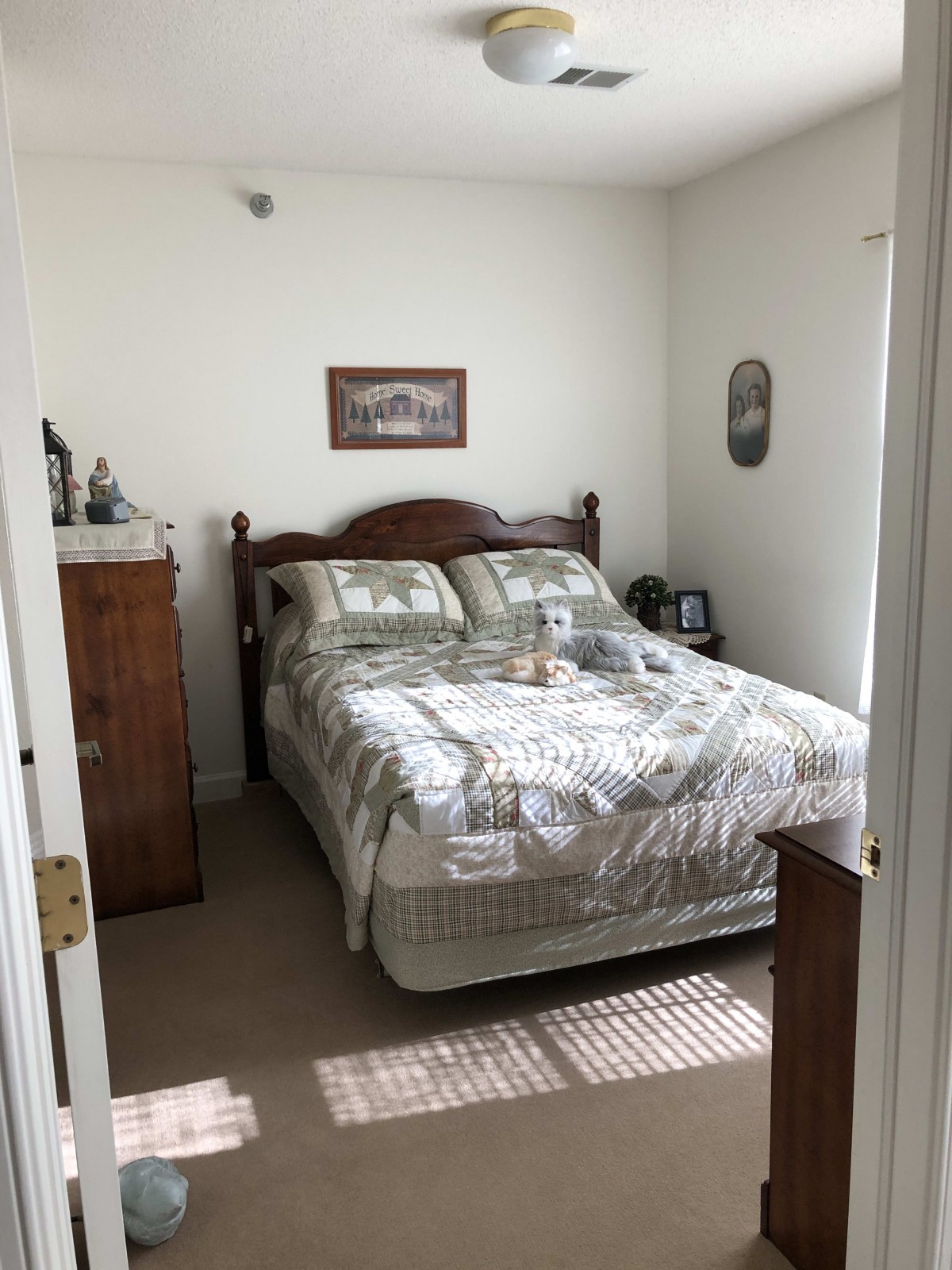 A cozy bedroom with a neatly made bed, wooden furniture, and decorative elements.