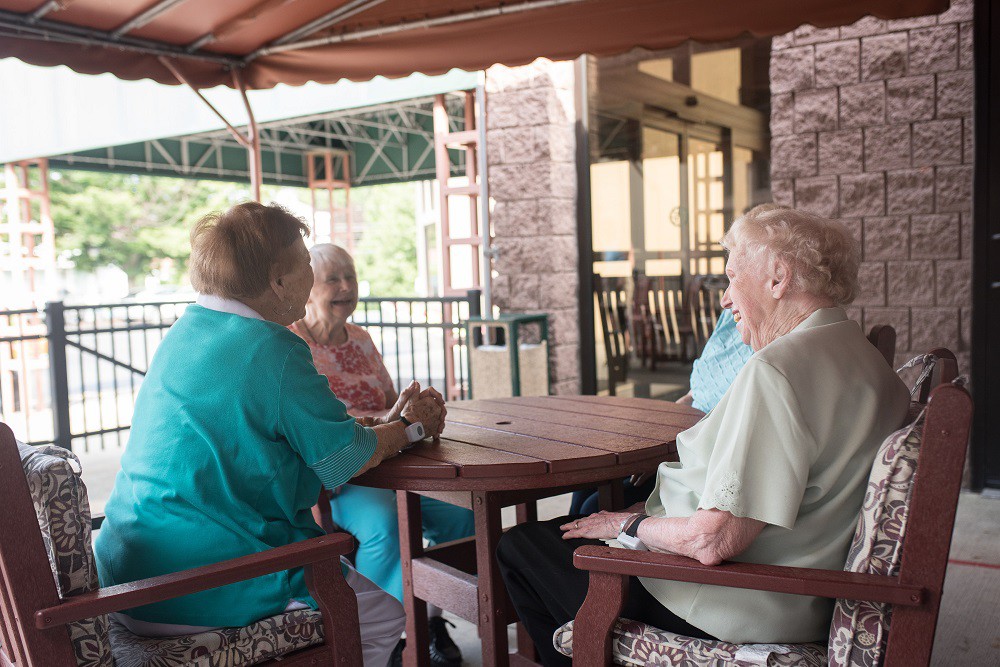 A group of seniors sitting together and socializing on a patio.
