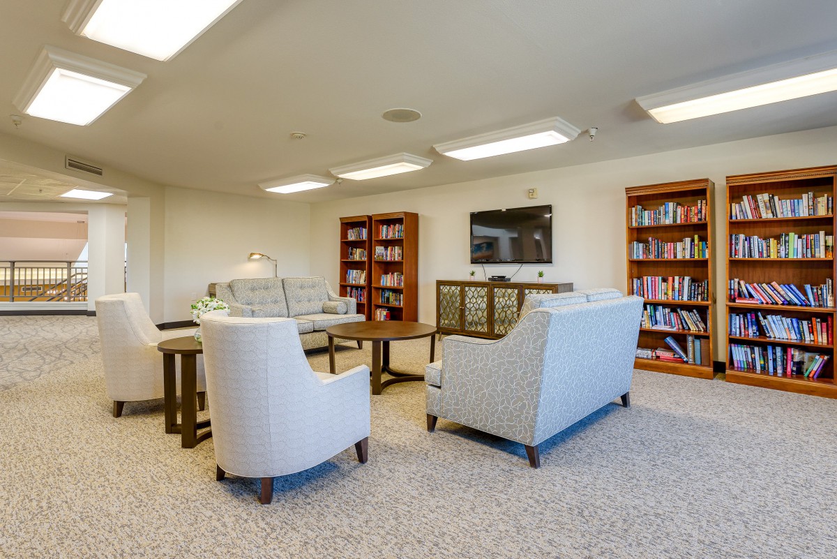 A cozy library-style seating area with bookshelves, comfortable chairs, and a coffee table.