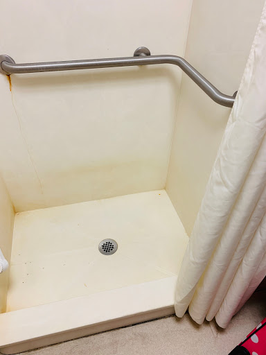 A view of a shower space showing signs of wear and staining.