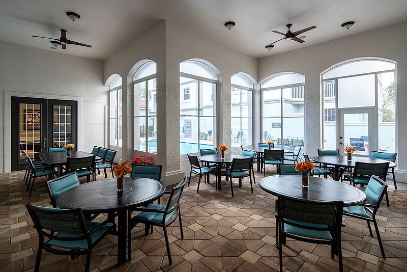 A bright dining area with tables and chairs, featuring large windows and stylish decor.