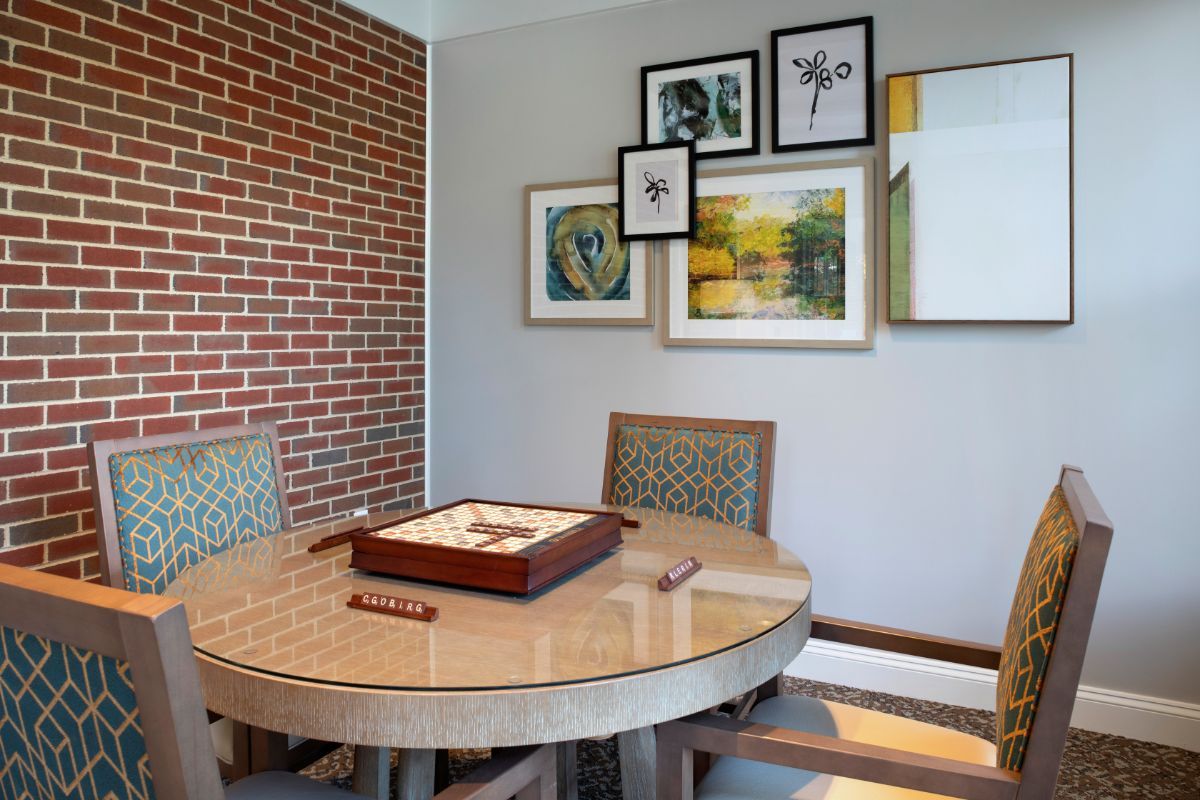 A modern dining area featuring a round table, upholstered chairs, and an eclectic gallery wall with various artworks.