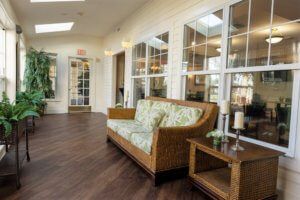 A cozy living room with a wooden sofa, side table, and large windows letting in ample light.