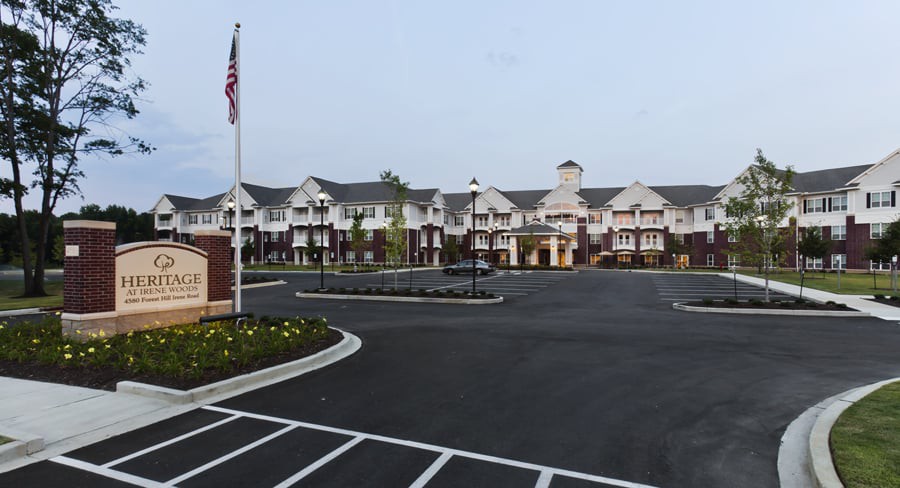 A large building complex with a spacious parking lot and an American flag in front.