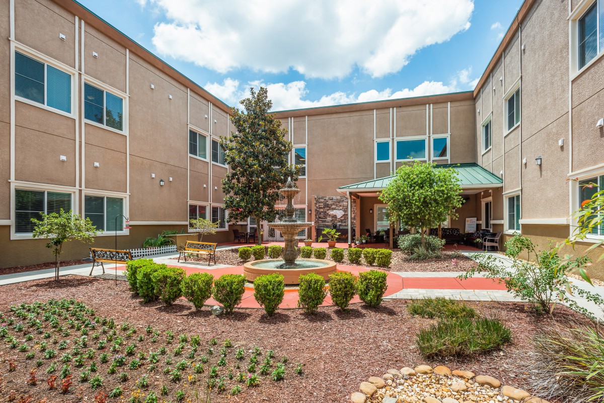 A view of a landscaped courtyard with a brick building in the background.
