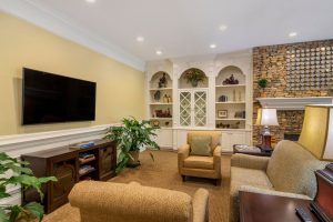 A cozy living room with comfortable seating, built-in shelves, and a large television.