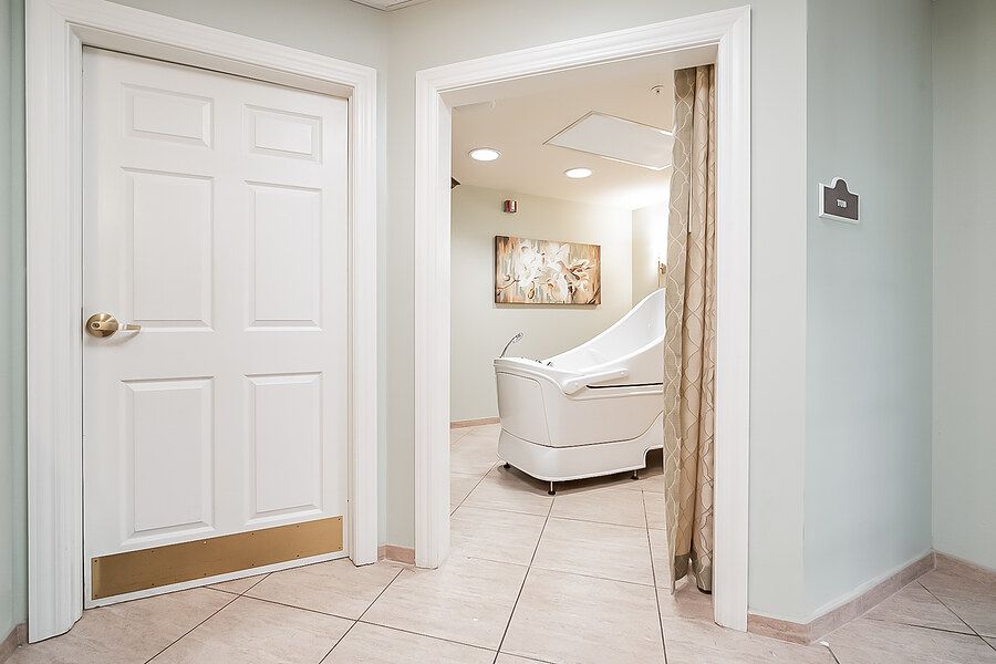 A modern spa room with a white massage table and tile flooring.