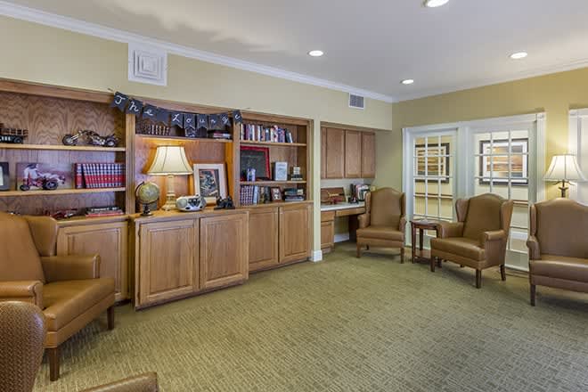 A cozy room with wooden bookshelves, comfortable chairs, and decorative items.