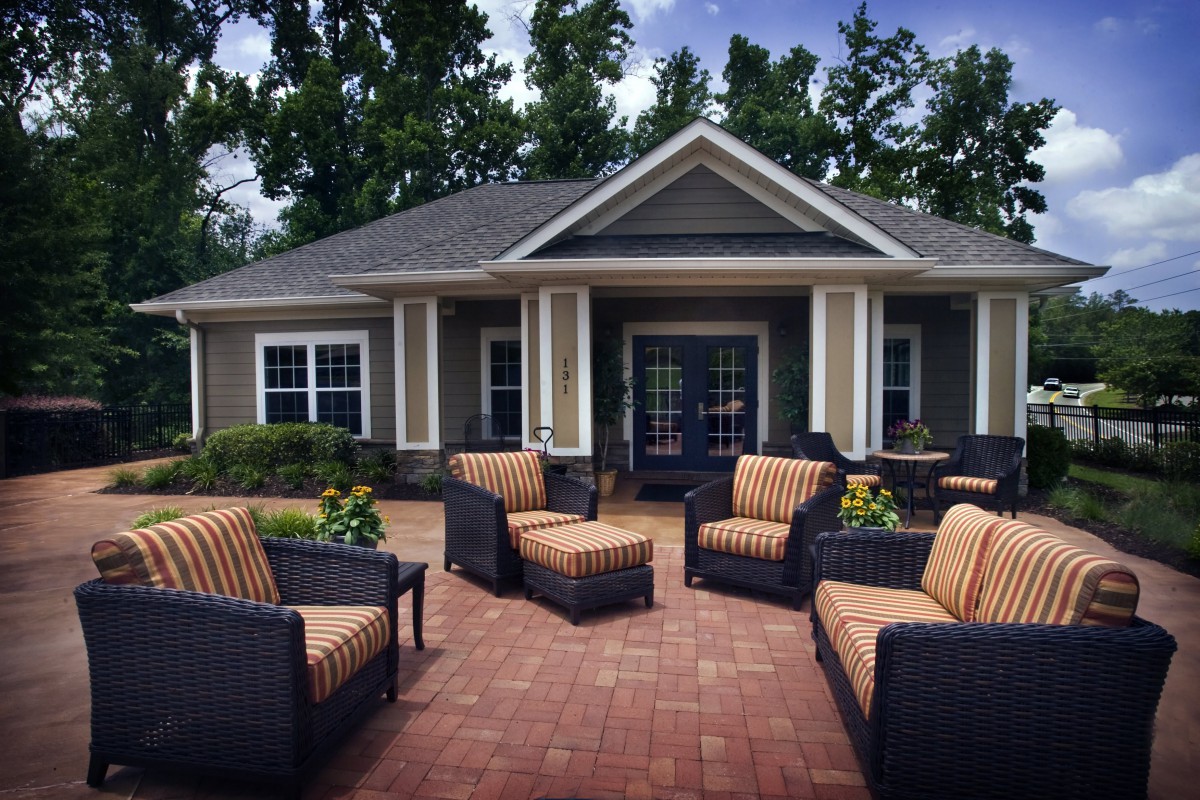 A cozy outdoor patio with wicker furniture arranged in front of a charming house.