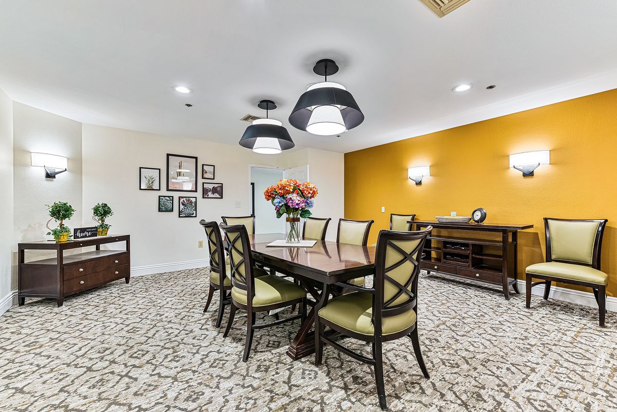 A stylish dining room with a wooden table, cushioned chairs, and elegant lighting.
