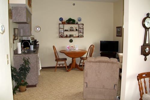 A cozy living space featuring a dining table with chairs, a TV, and decorative shelving.