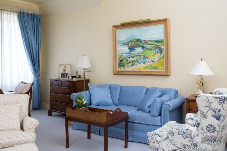 A cozy living room featuring a blue sofa and a vibrant landscape painting above it.