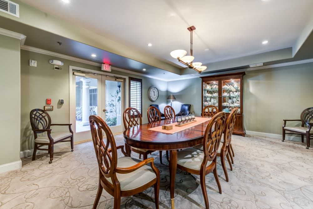 A well-appointed dining room with a polished wooden table, elegant chairs, and an overhead chandelier.