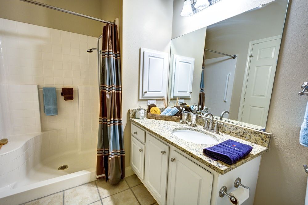 A clean and modern bathroom with a shower, sink, and countertop.