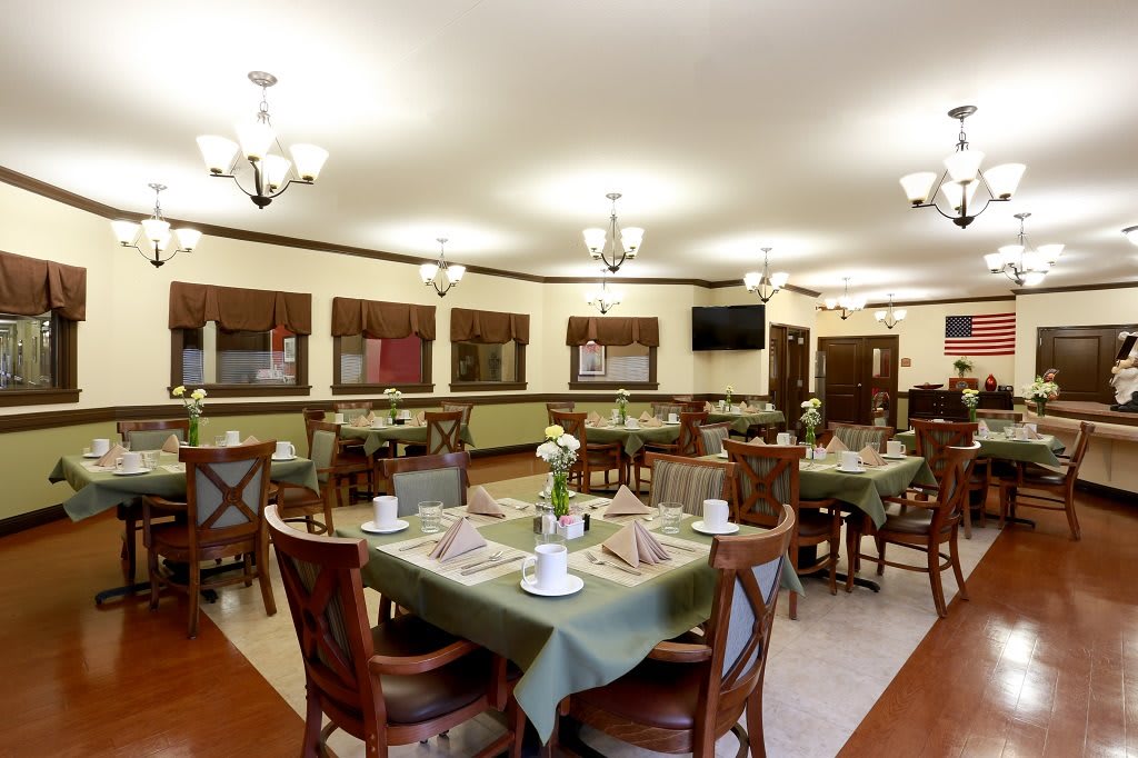 A cozy dining area with neatly arranged tables and chairs, featuring elegant table settings.