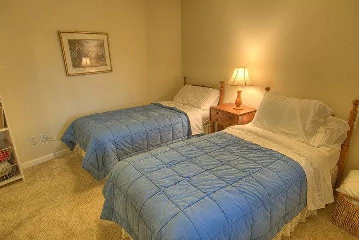 A cozy bedroom with twin beds and a warm lamp illuminating the nightstand.