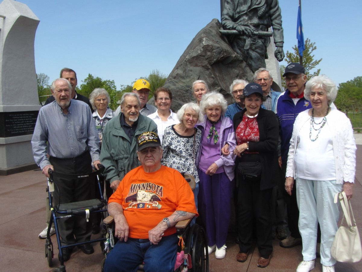 A group of elderly people gathered outdoors near a monument.