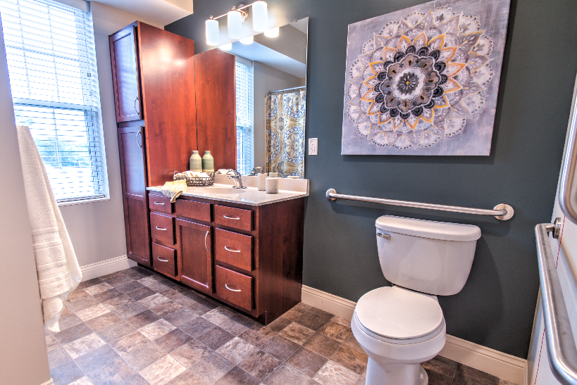 A modern bathroom featuring a sink with a wooden cabinet, a toilet, and decorative wall art.