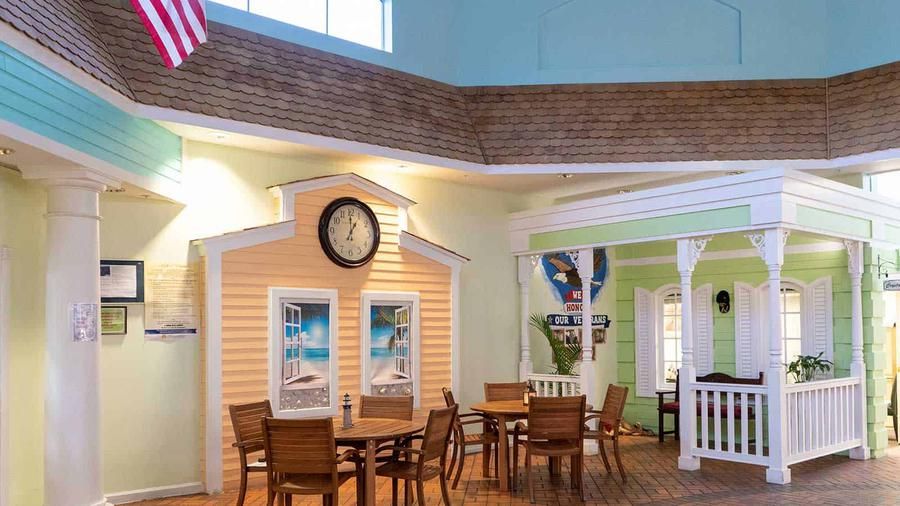A cozy indoor dining area with tables and chairs, featuring decorative walls and a clock.