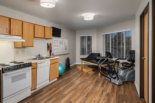 A modern home gym featuring exercise equipment and a kitchen area, illuminated by natural light.