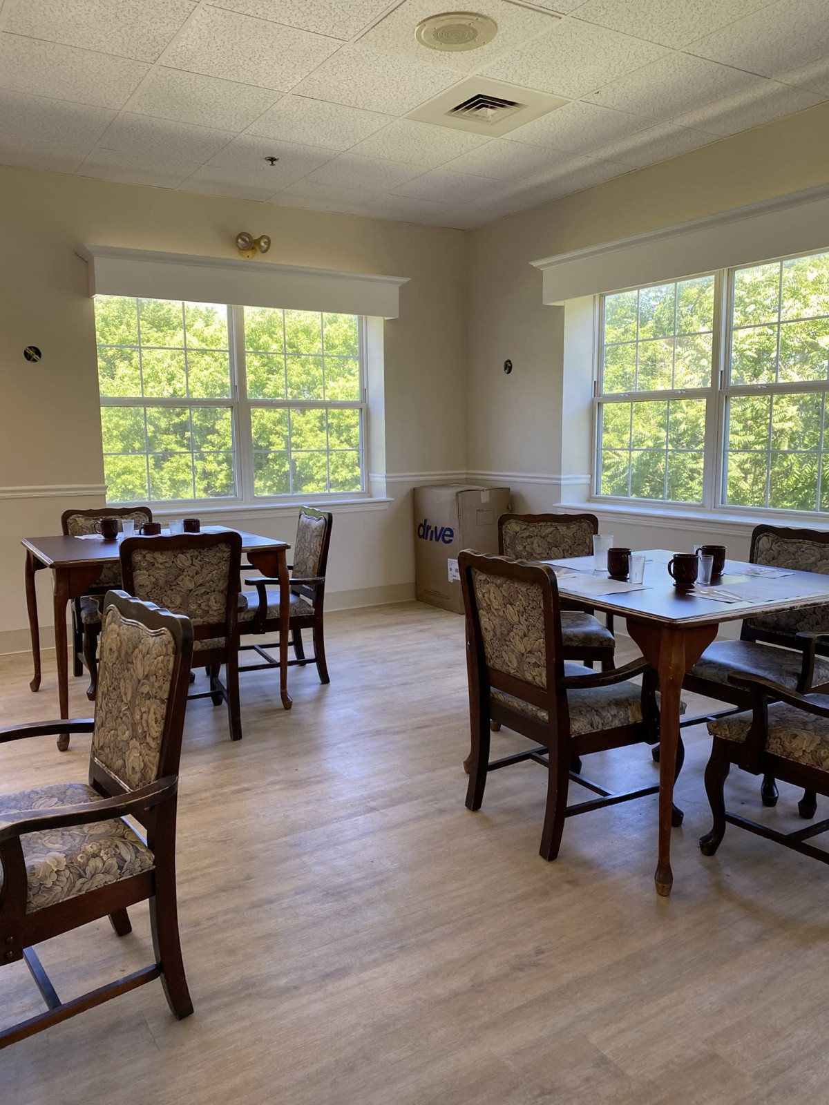 A bright dining area with multiple tables and chairs, illuminated by natural light from large windows.