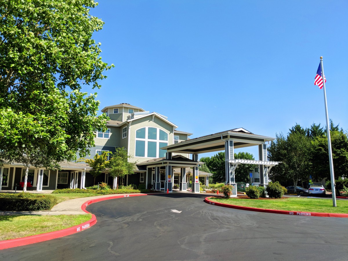 A modern building with a driveway and surrounding greenery.