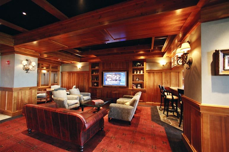 A luxurious home theater with wood paneling, comfortable seating, and a small bar area.