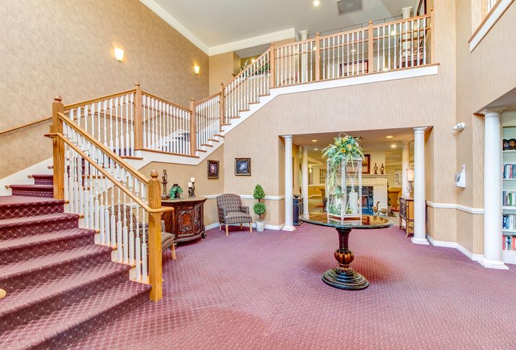 A spacious lobby area with a grand staircase, elegant furniture, and decorative elements.