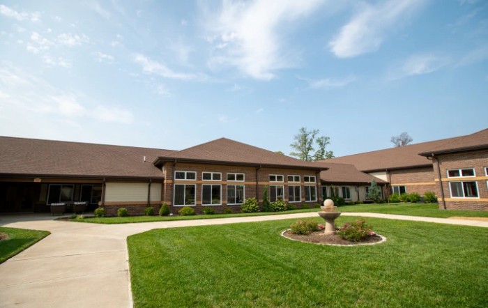 A residential building with a well-maintained lawn and driveway under a clear blue sky.