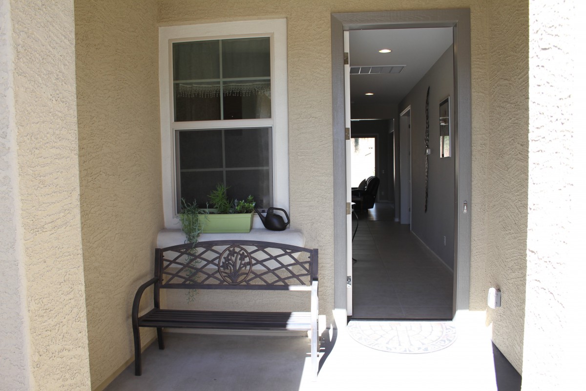 A bench is placed near a window with a planter on top, beside an open door leading to a hallway.