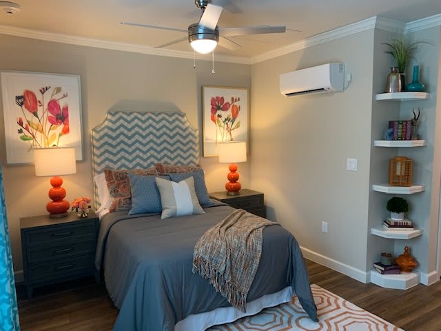 A modern bedroom with a stylish bed, decorative lamps, and artwork on the walls.