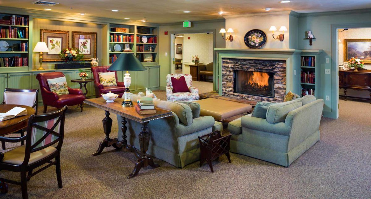 A cozy living room with a warm fireplace, comfortable seating, and a well-stocked bookshelf.