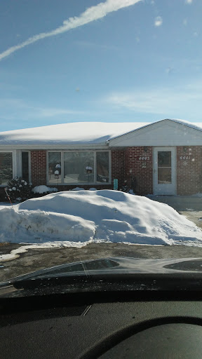 A cozy house partially covered in snow on a sunny winter day.
