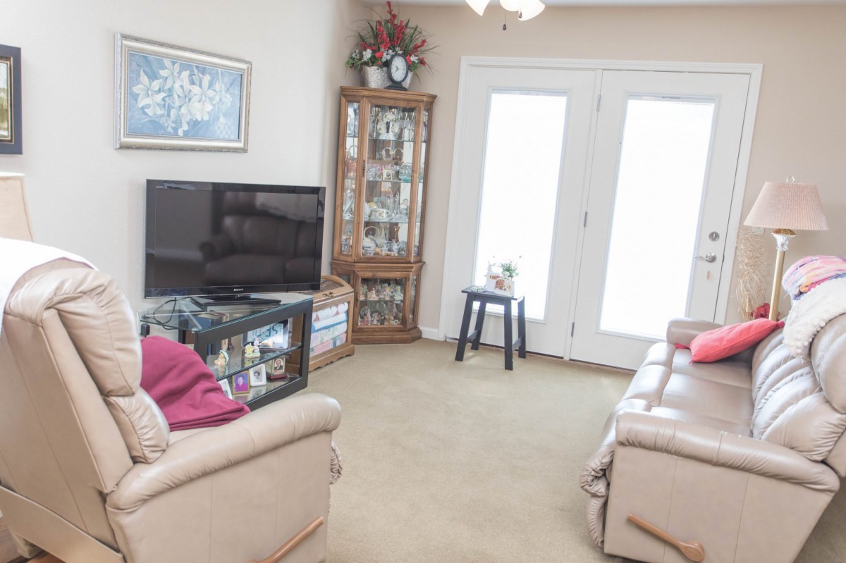 A cozy living room featuring sofas, a television, and a glass cabinet filled with decorations.