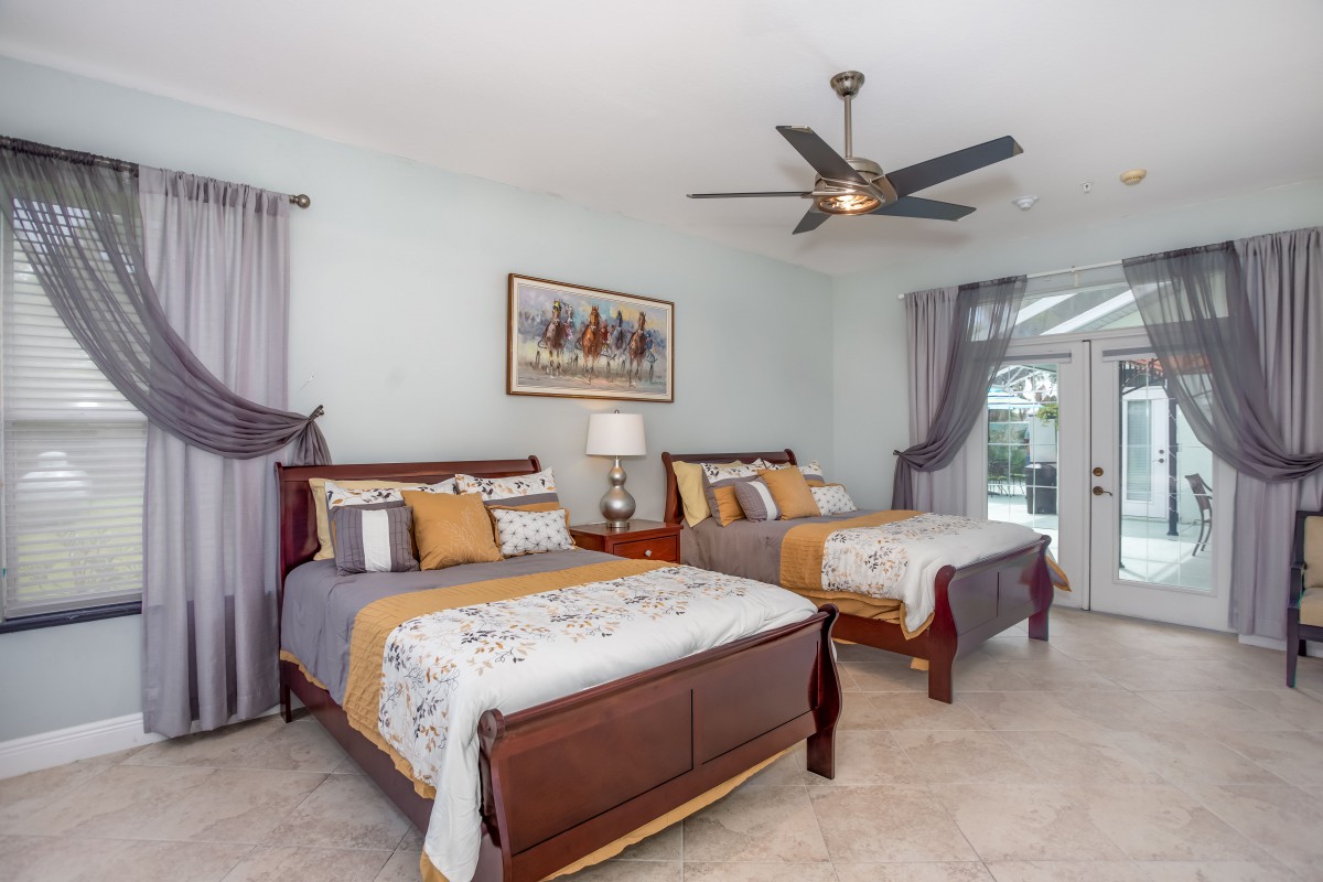 A well-decorated bedroom with two beds, a ceiling fan, and elegant decor.