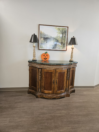 A beautifully styled wooden cabinet adorned with decorative lamps and a festive pumpkin, complemented by an artistic wall piece.