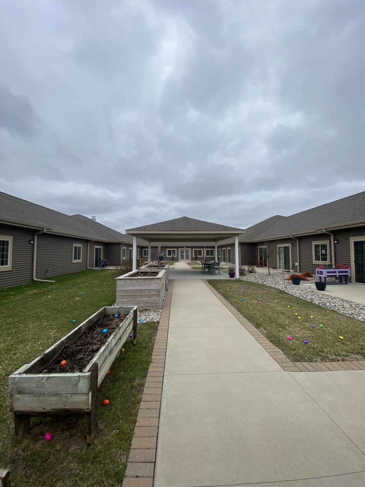 A courtyard with garden beds and surrounding buildings under an overcast sky.
