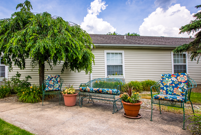 A cozy backyard patio with seating and vibrant potted plants.