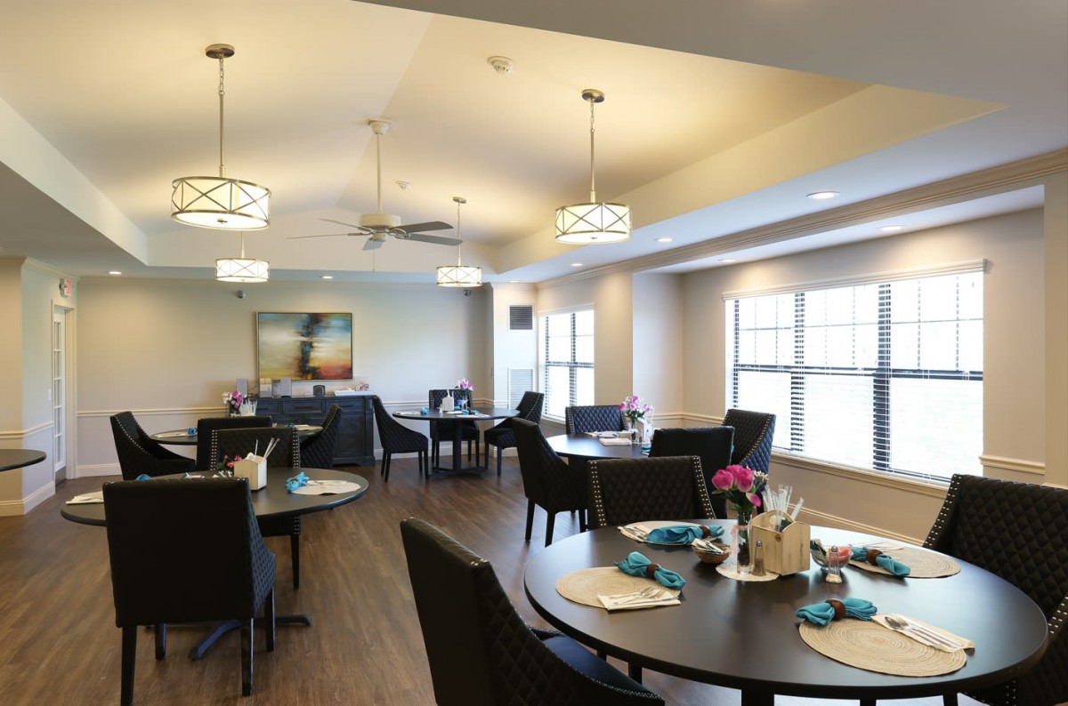 A well-lit dining room with neatly arranged tables and chairs, featuring modern decor.