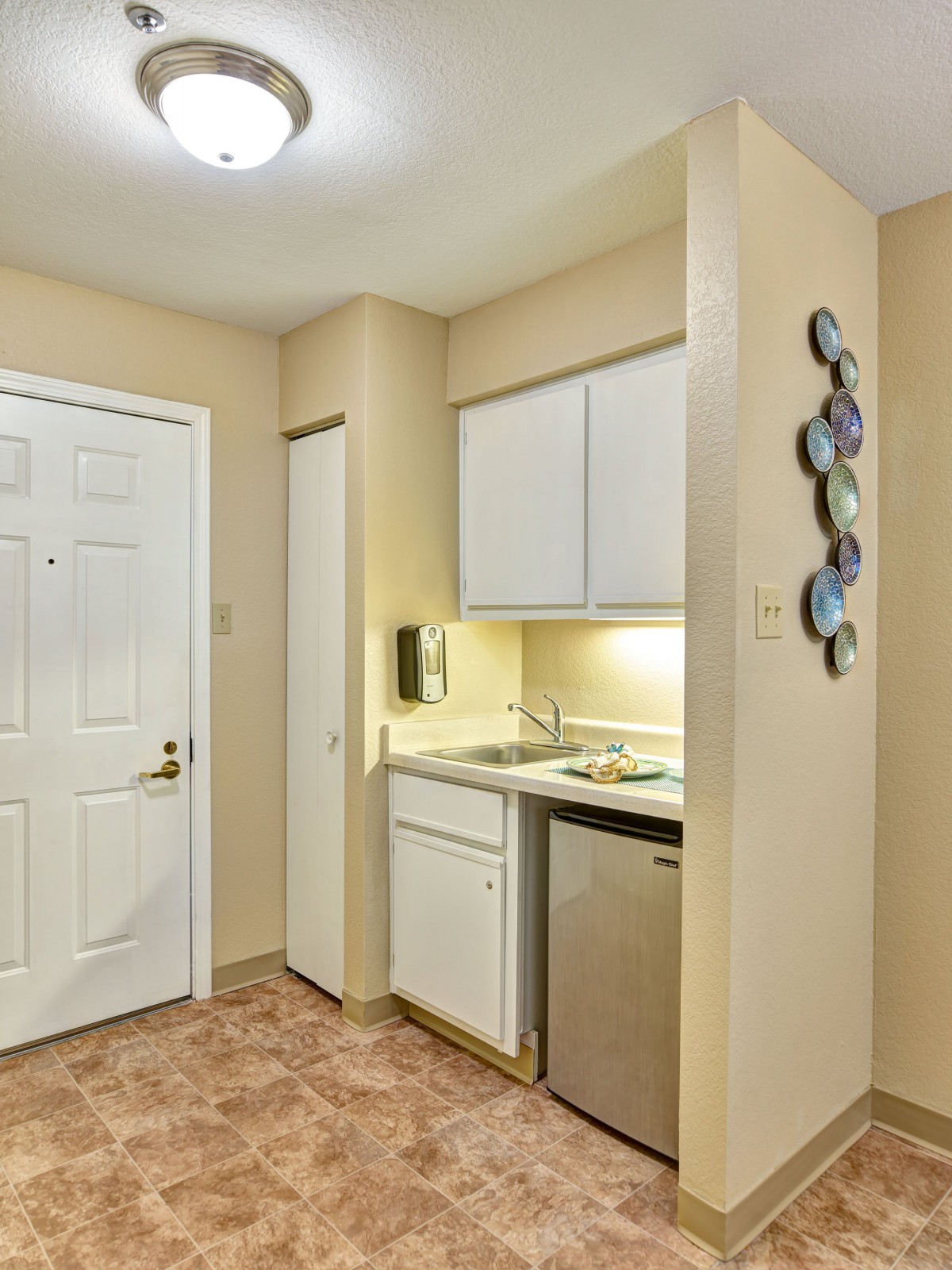 A compact kitchen area with white cabinets, a sink, and a dishwasher.
