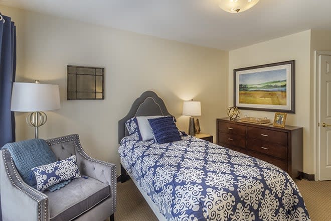 A cozy bedroom featuring a single bed with patterned bedding, complemented by stylish decor and artwork.