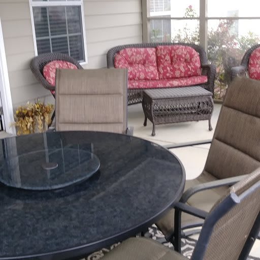 An outdoor patio featuring a glass table and cushioned seating.