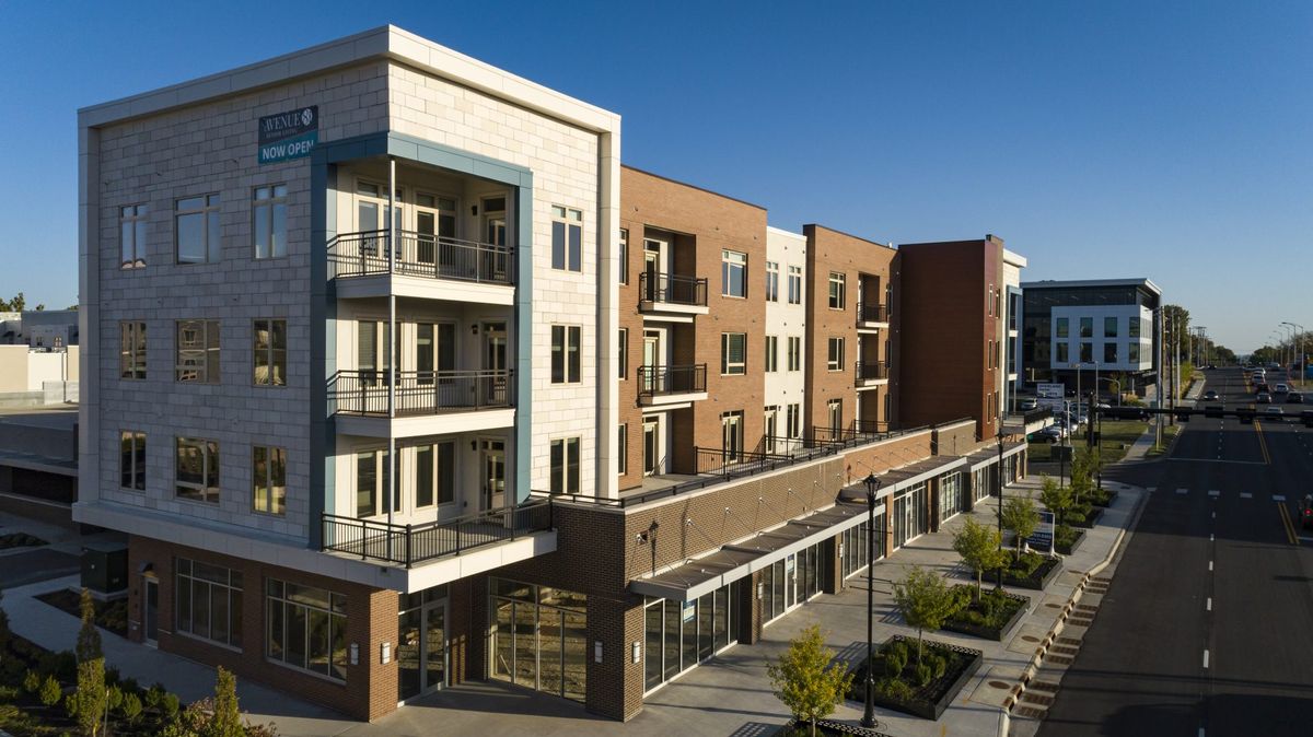 A modern apartment building with multiple balconies and commercial space on the ground floor.