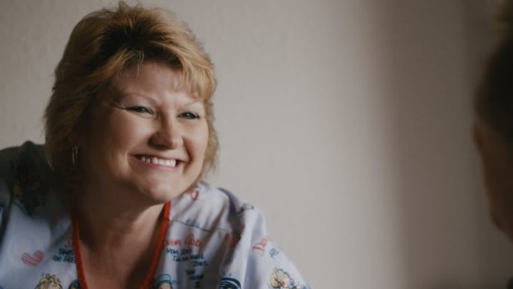 A woman with short hair smiling indoors.