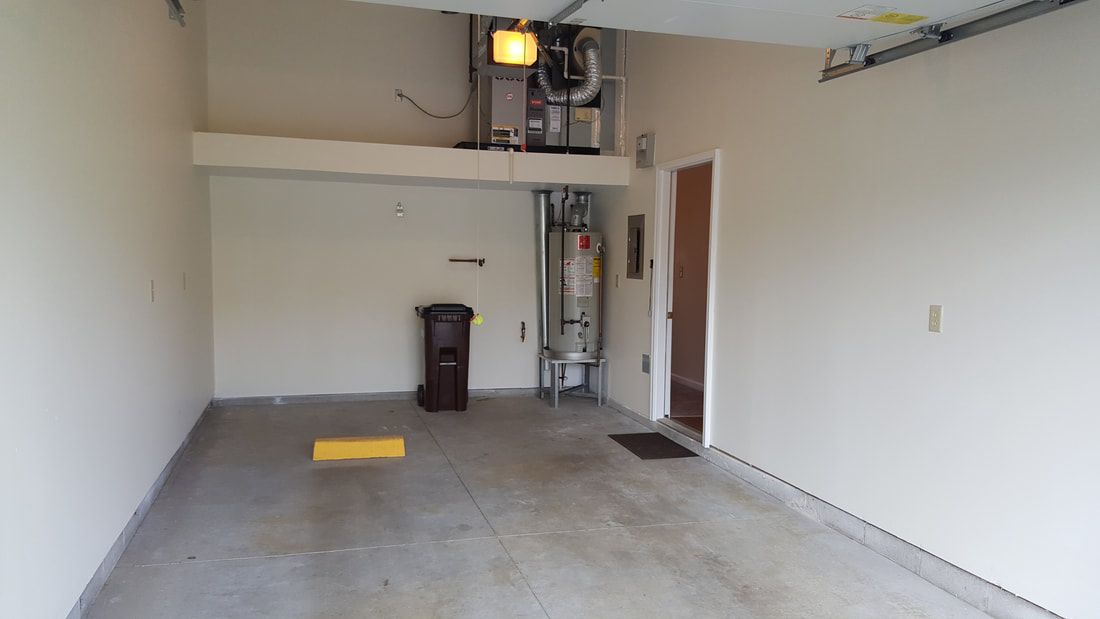 An empty garage with a visible water heater and utility setup.